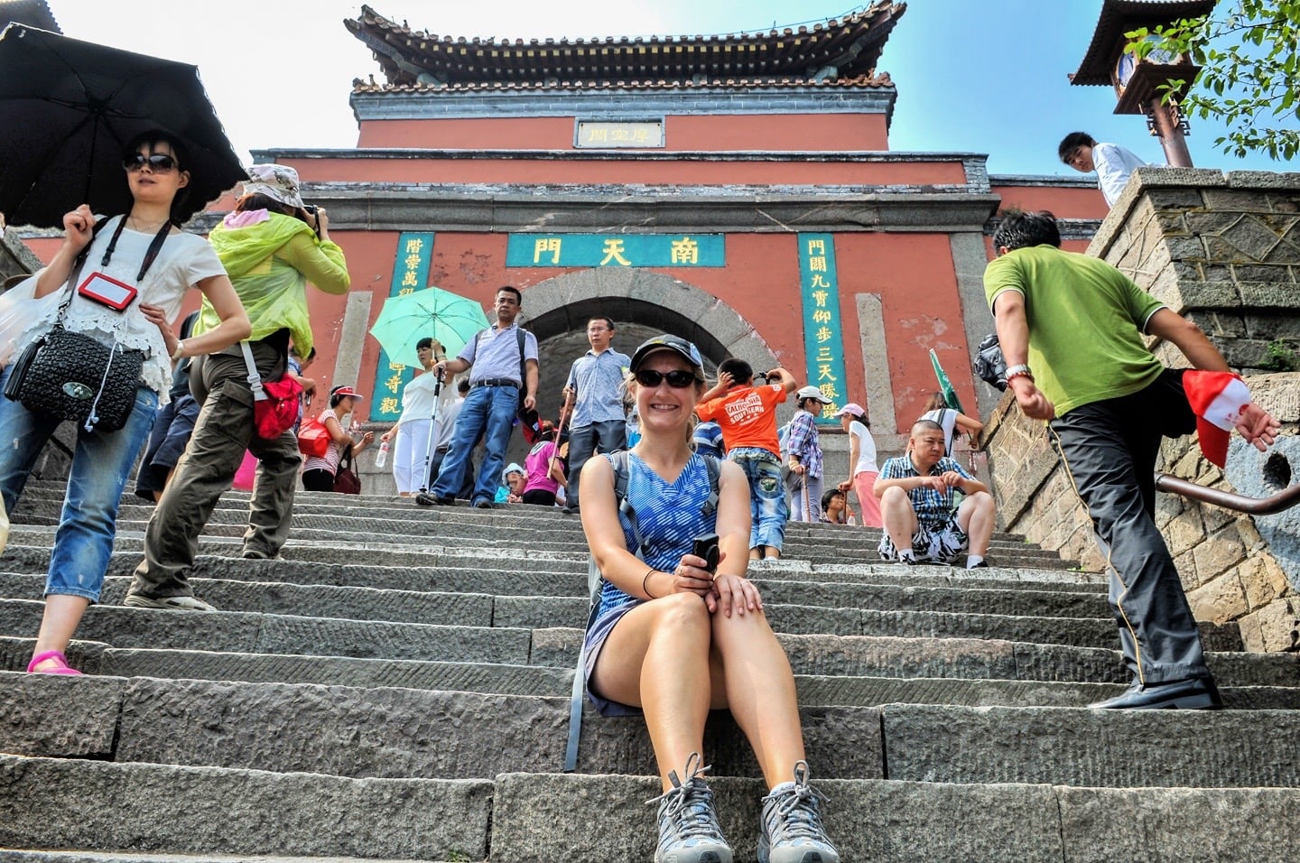 Woman sitting on stairs in front of a Chinese archway