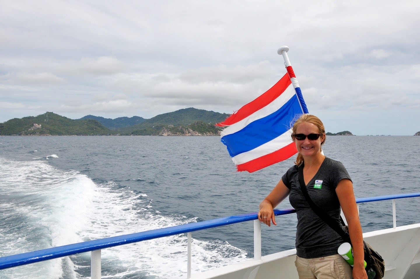 woman on ferry with Thai flag and island