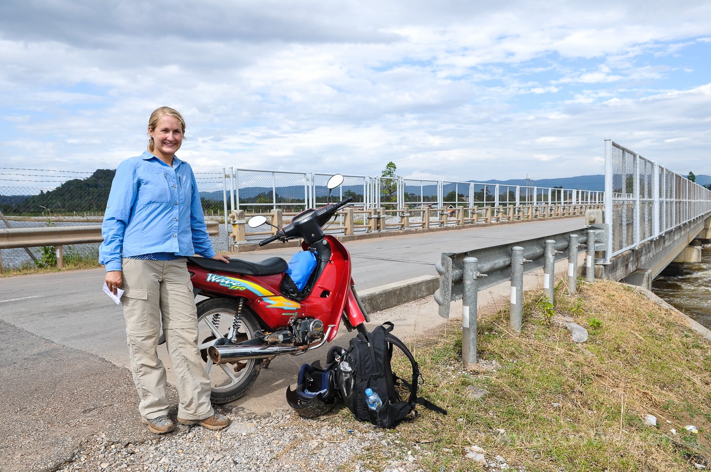 standing near motorbike near a bridge in laos