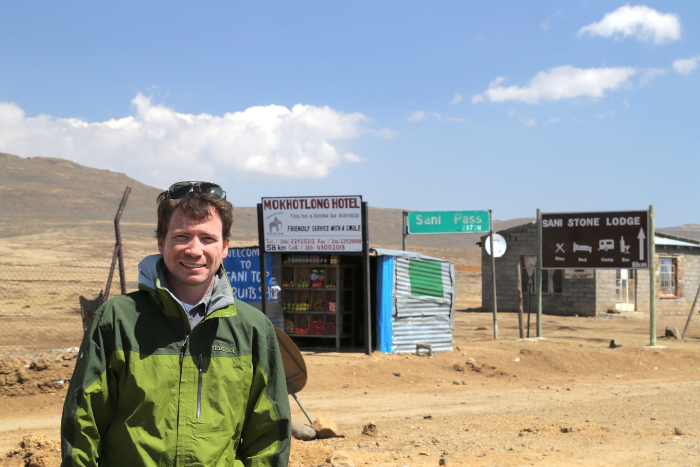 standing in front of signs to Sani Pass and Lesotho