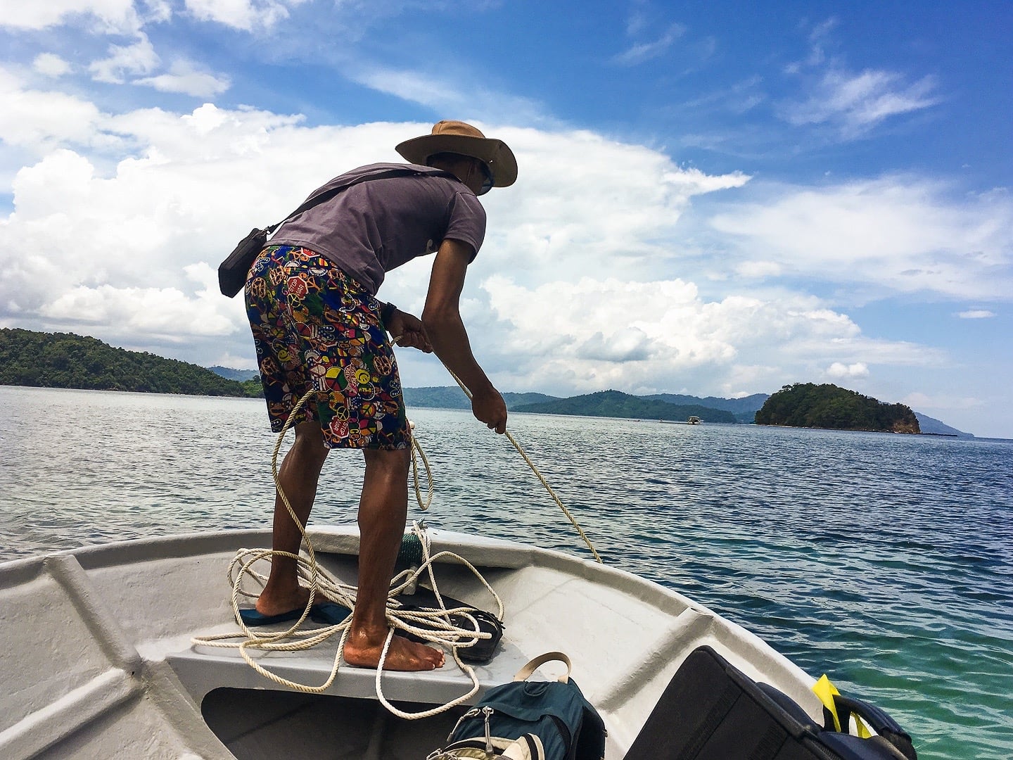 man pulling anchor up on boat