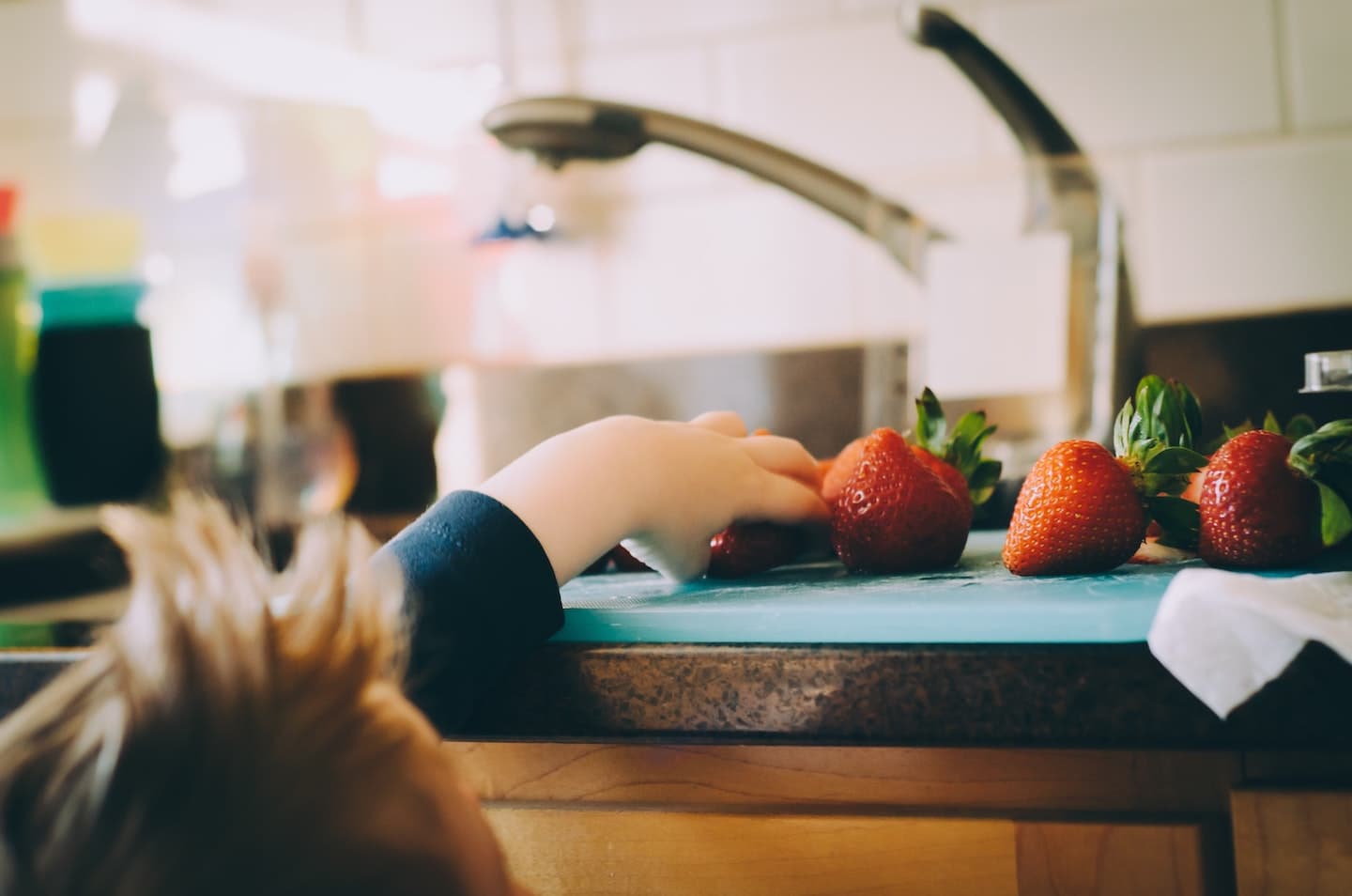 strawberries on counter with child