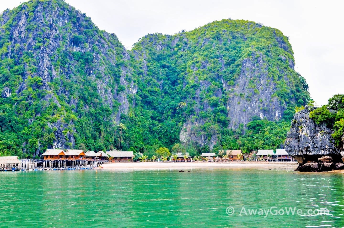 stilted bungalow on beach with karst cliff backdrop