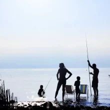 two people traveling with a toddler at a lake and fishing
