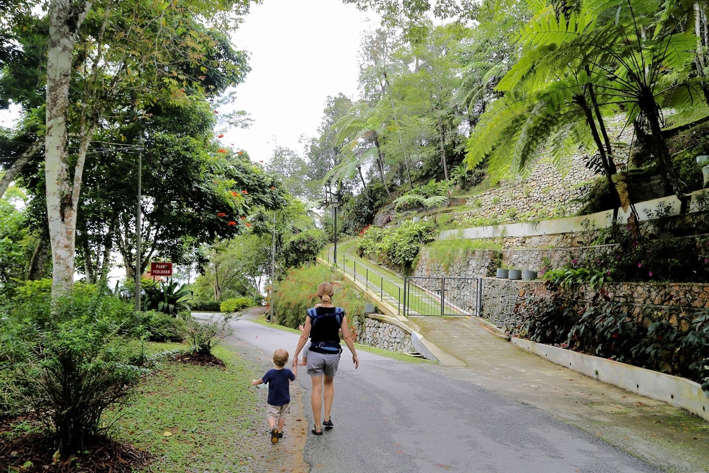 mother and child walking on a road near a hill