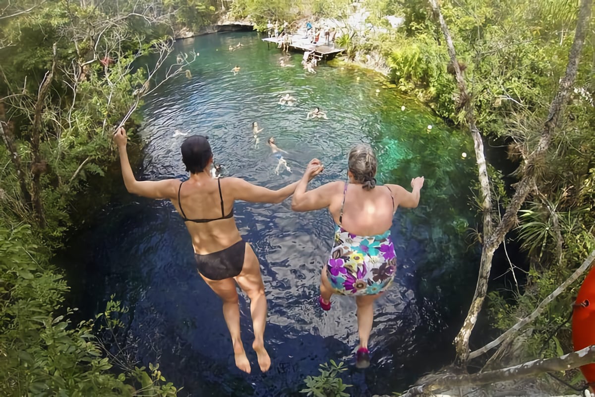 two people jumping into a natural pool
