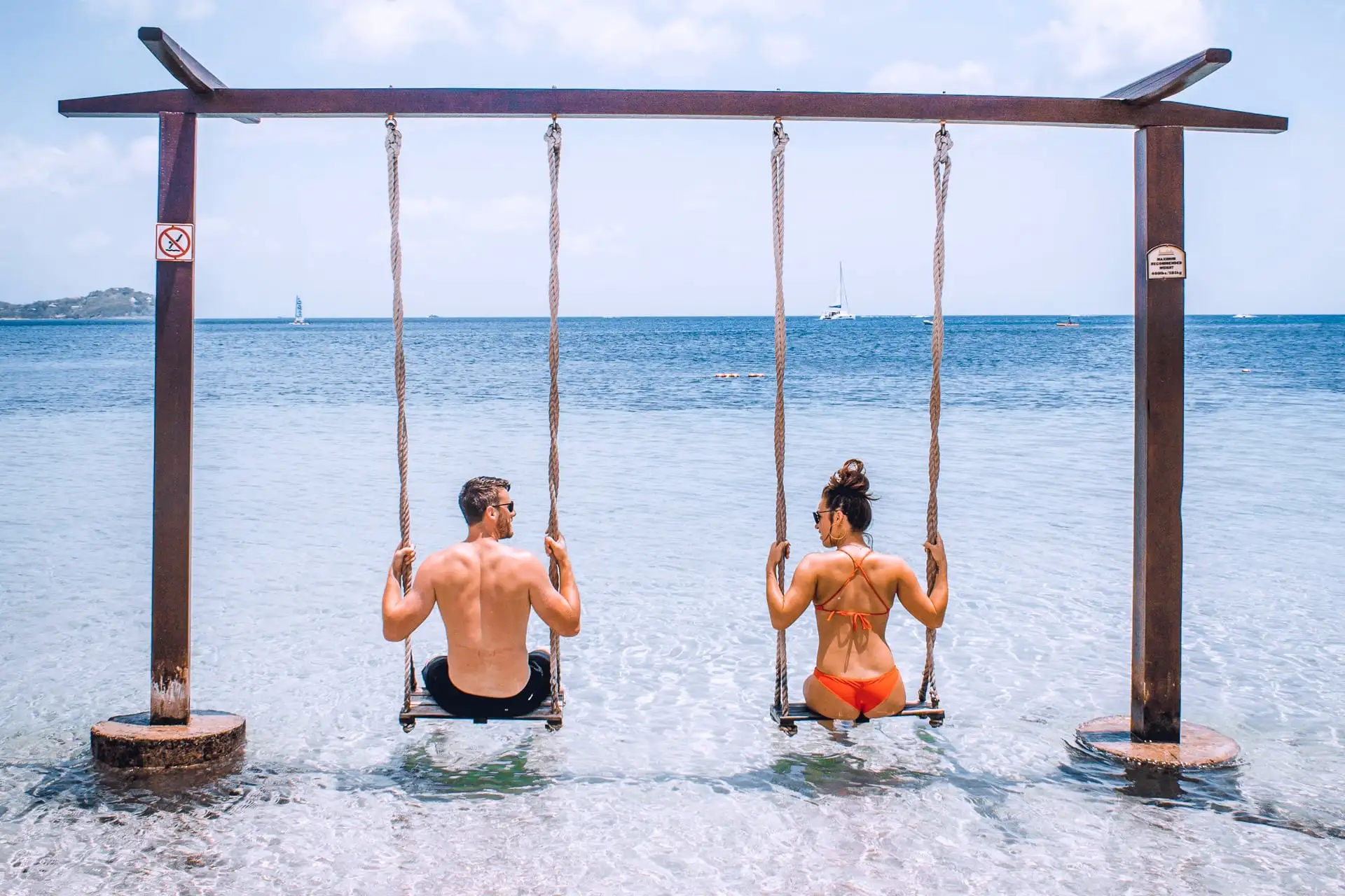 St Lucia honeymoon couple swinging over clear water