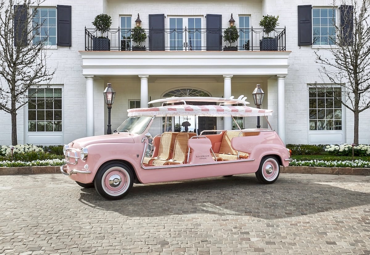 pink shuttle car in front of white hotel