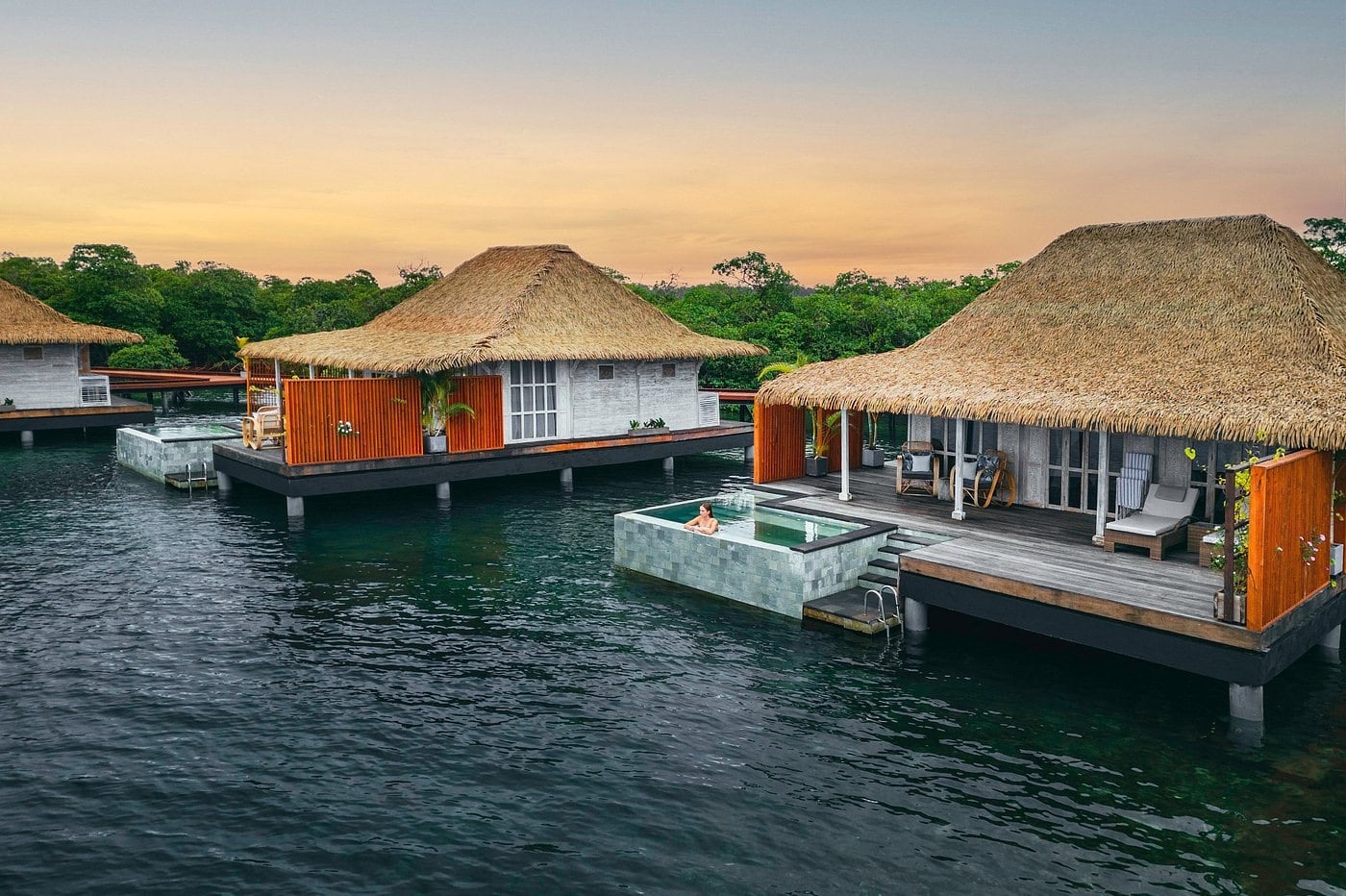 two Caribbean water bungalows at sunset
