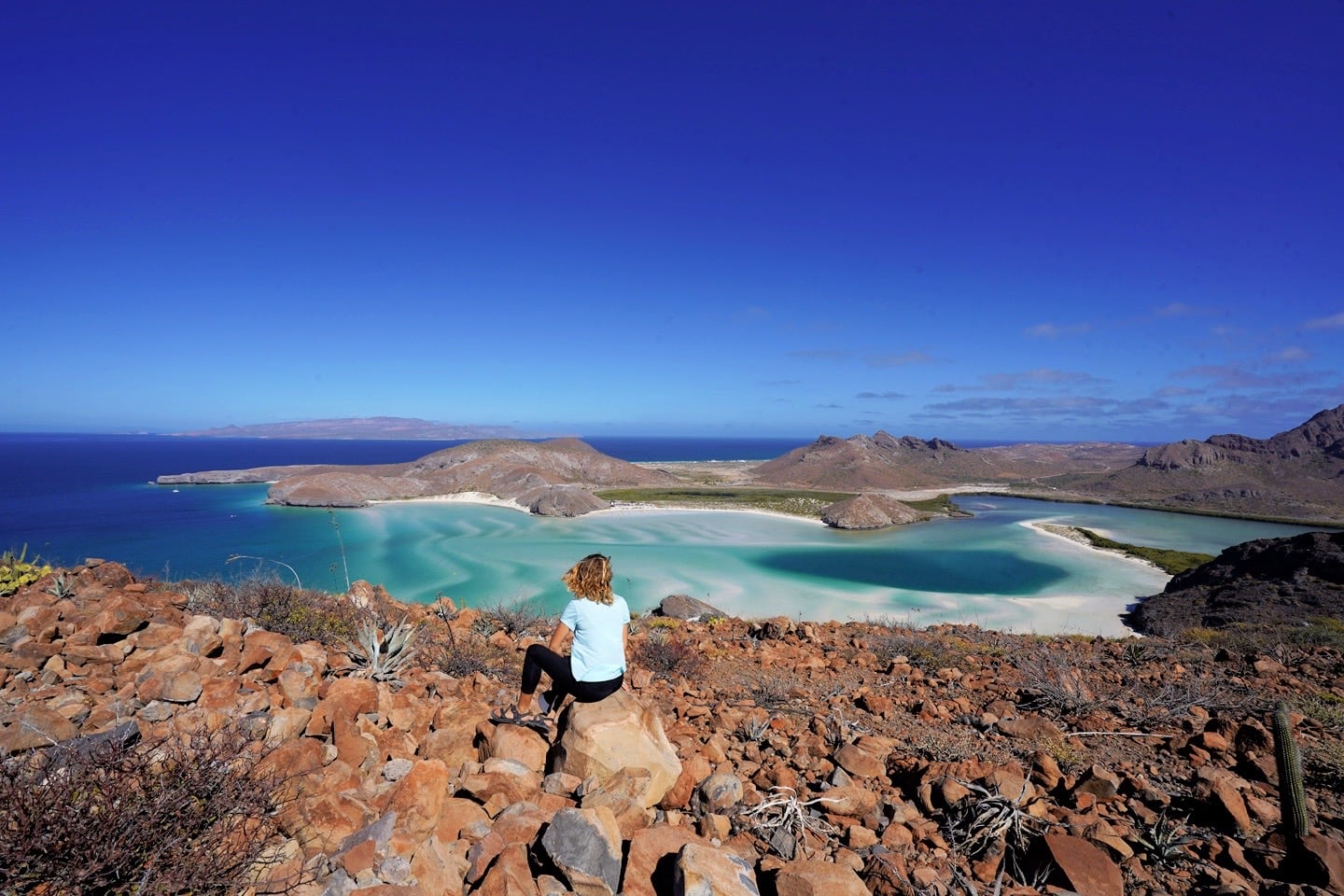 woman sitting on viewpoint overlooking sea