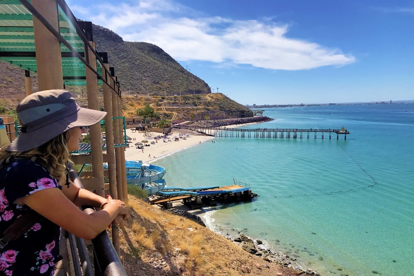 woman looking out at sea near beach with pier