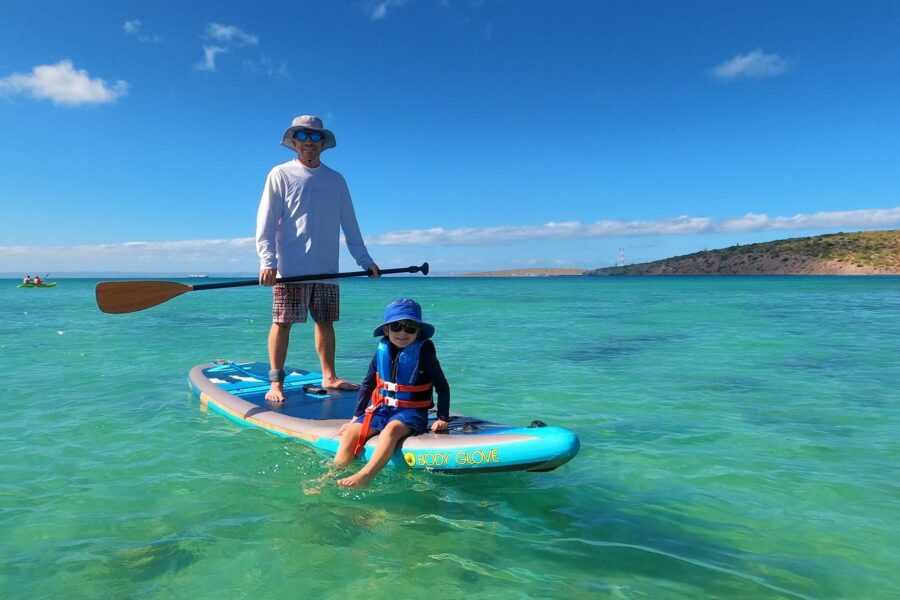paddle boarder and child on turquoise water